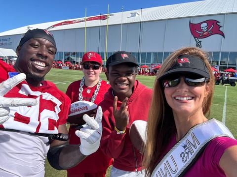 Kellie Lightbourn in her sash taking a selfie with new friends outdoors