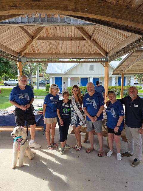 Kellie Lightbourn in her sash with community service volunteers under a park pavilion