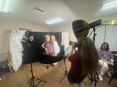 Two girls in tiaras and sashes posing at a photo-booth shoot