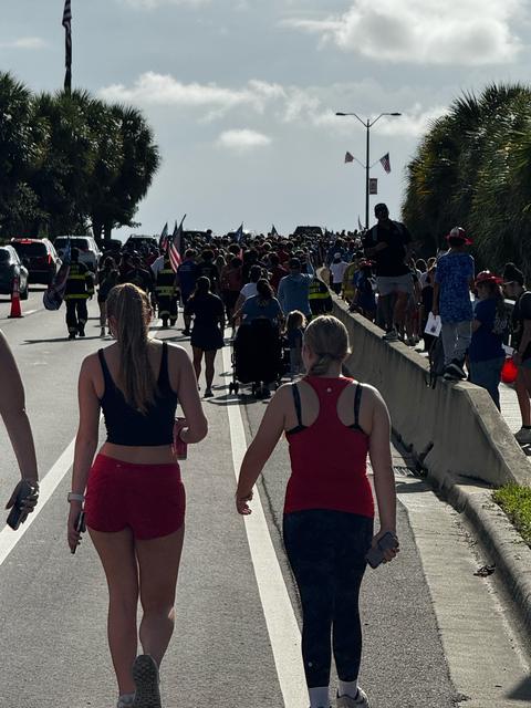 A large community walk with flags and firefighters
