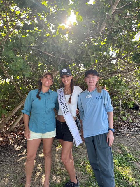 Kellie Lightbourn in her sash with two conservation volunteers beneath sea grape trees
