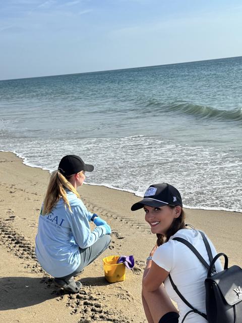 Kellie Lightbourn smiling on the beach beside a conservation worker