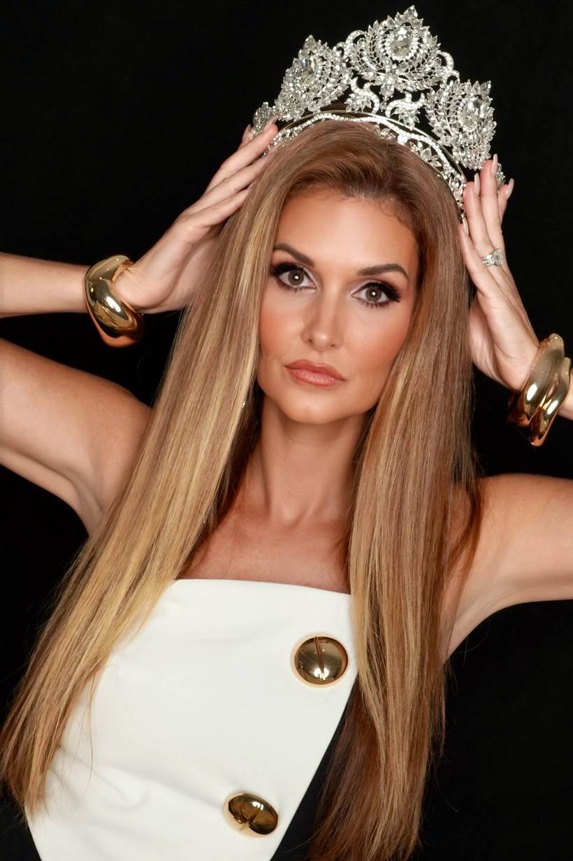 Kellie Lightbourn, Mrs. Universe 2026, in white and gold with her hands on the crown