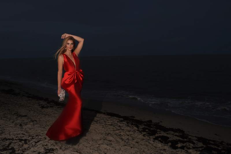 Kellie Lightbourn, Mrs. Universe® 2026, in a red bow gown on the beach at night