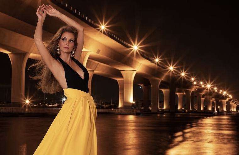 Kellie Lightbourn, Mrs. Universe® 2026, in a yellow gown beneath a lit bridge at night