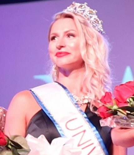 A crowned titleholder on stage with roses