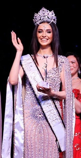 A crowned titleholder waving on stage
