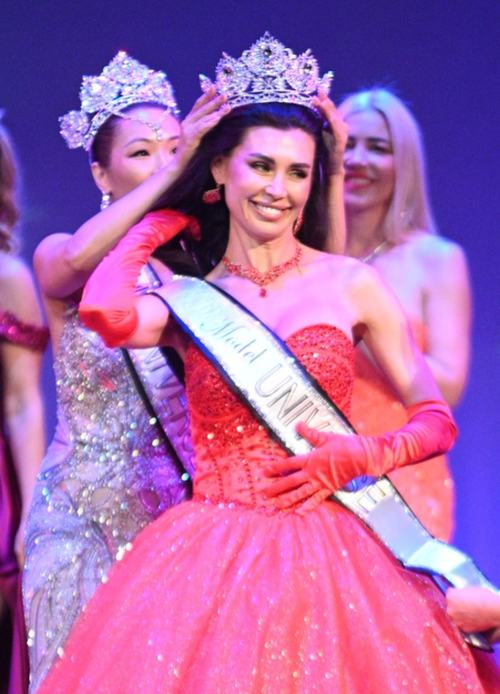 A titleholder in a pink ball gown being crowned on stage
